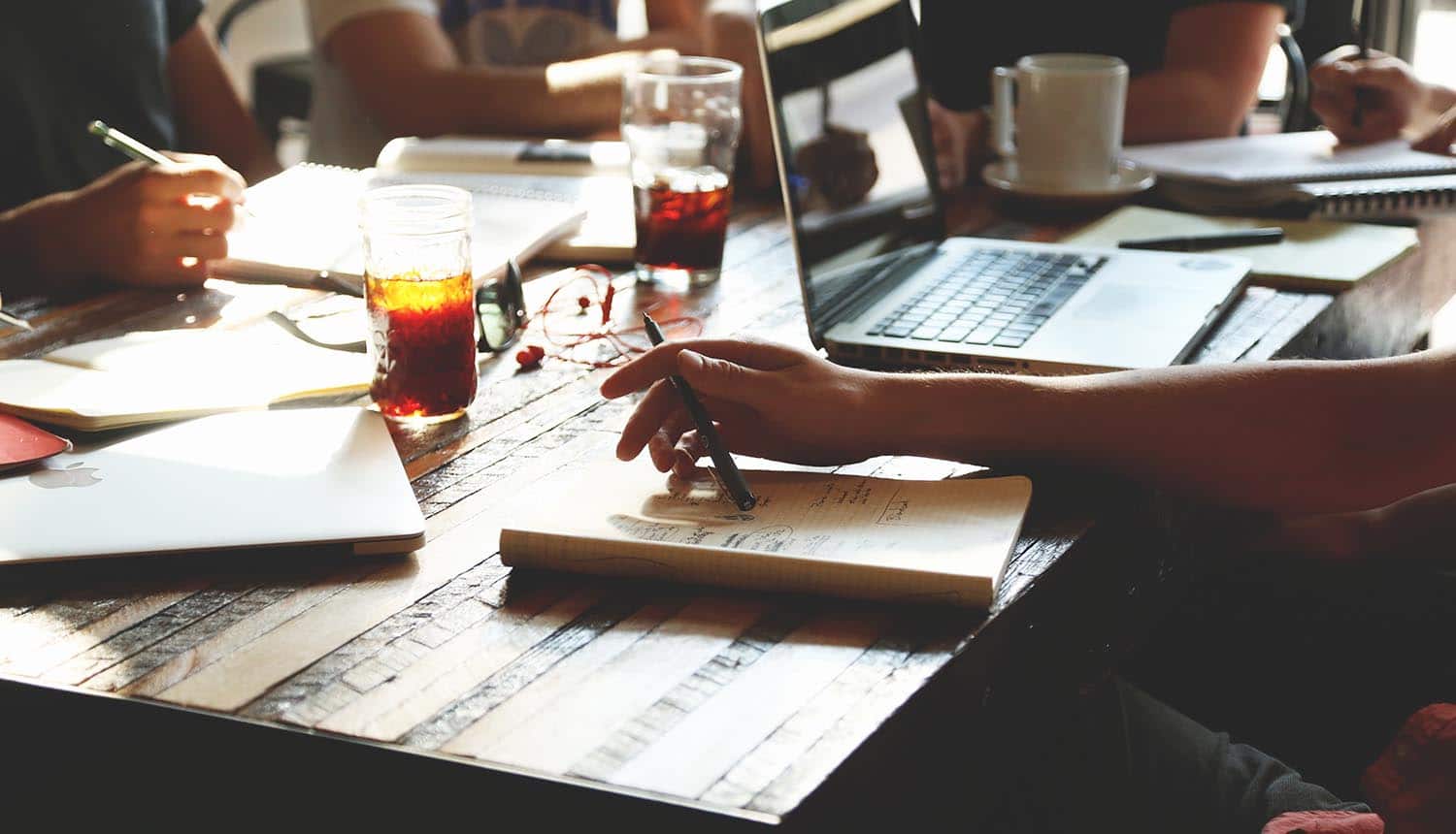 Image of entrepreneurs sitting around a table with laptops and notepads representing the privacy and data security mistakes made by start-ups