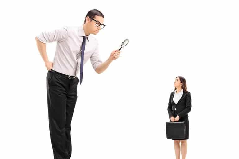 Image of big man using magnifying glass to scrutinize employee representing whether employers can find the employee privacy sweet spot