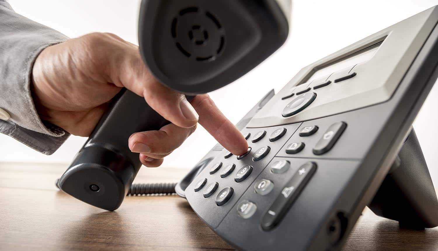 Image of man pressing buttons on desk phone representing the recent U.S. vs Apple case