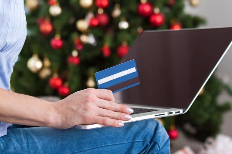 Image of woman holding credit card in front of laptop representing how online retailers are preparing for the holiday hacking season