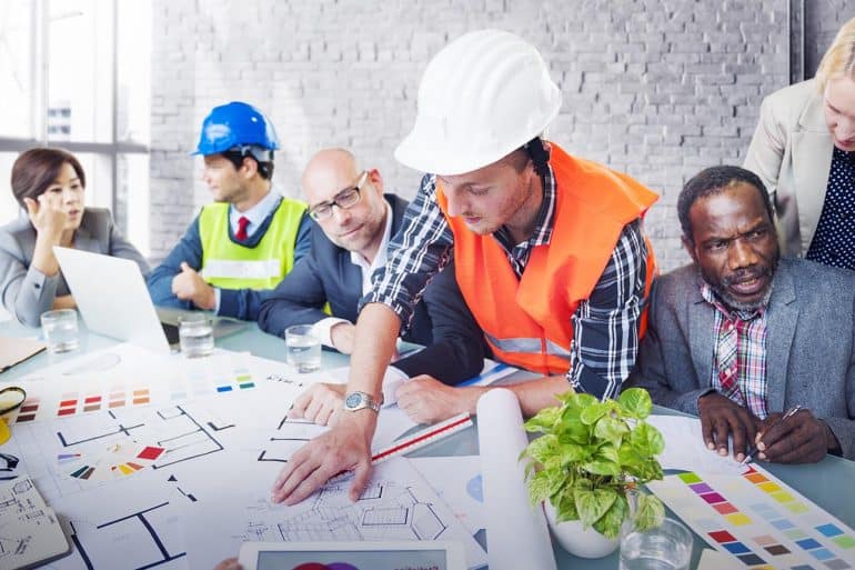 Image of team of engineers and business people looking at plans on a table representing the operationalising of the EU GDPR and Privacy by Design