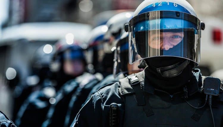 Image of police in riot gear representing government surveillance and the impact on security and privacy