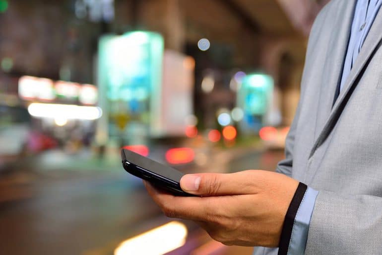 Image of businessman holding mobile phone representing the security menace of mobile communication devices for business executives