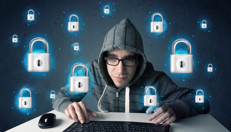 Image of hooded hacker in front of keyboard and surrounded by floating locks representing how to stop ransomware attacks