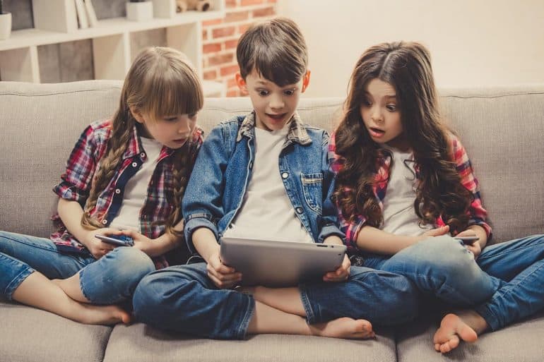 Image of kids with surprised look holding a tablet representing how Disney, the happiest place on earth, is facing problems for mobile apps for kids