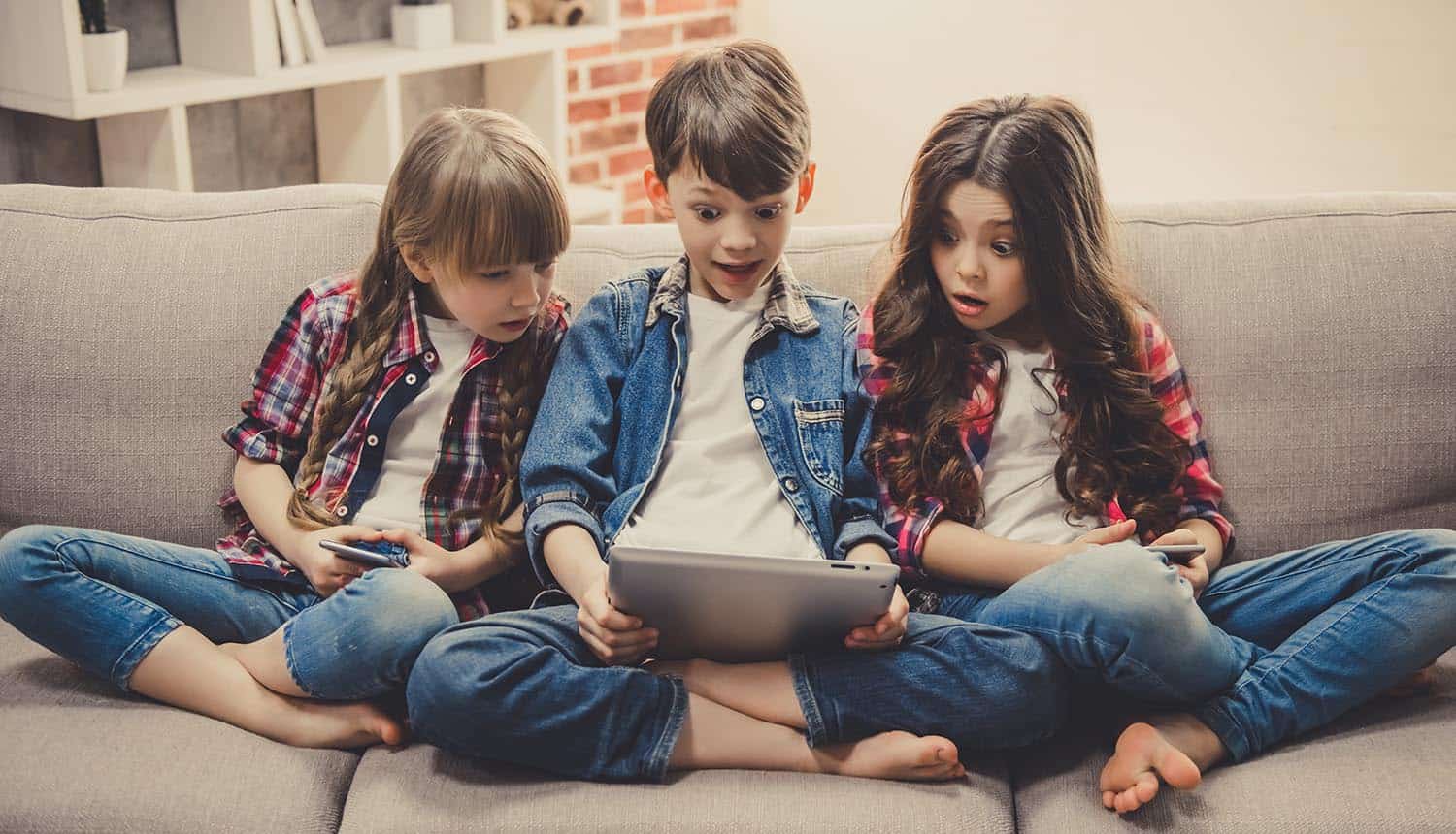 Image of kids with surprised look holding a tablet representing how Disney, the happiest place on earth, is facing problems for mobile apps for kids