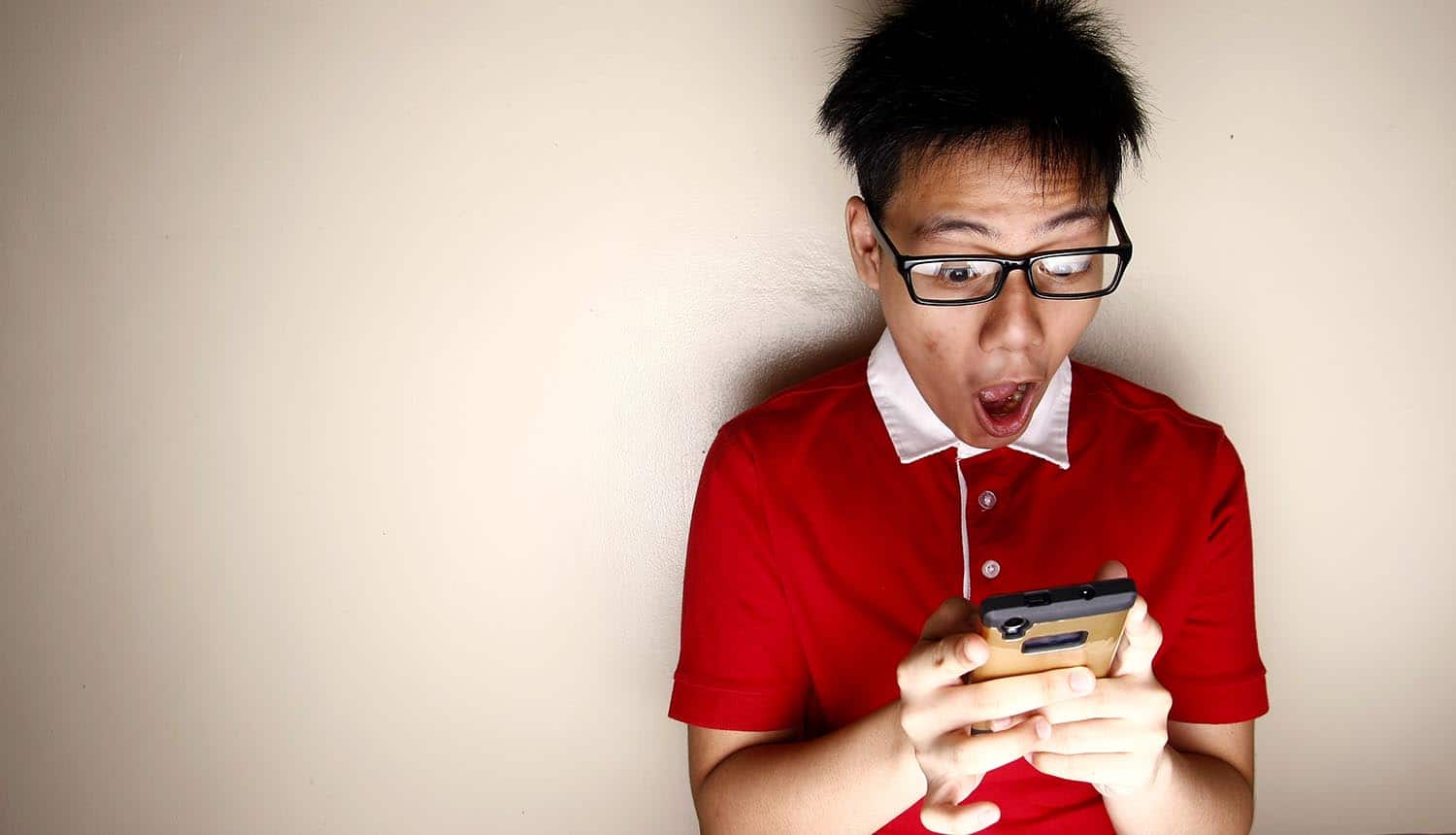Image of man with surprised look holding mobile phone representing what is given away based on privacy policies and terms of use
