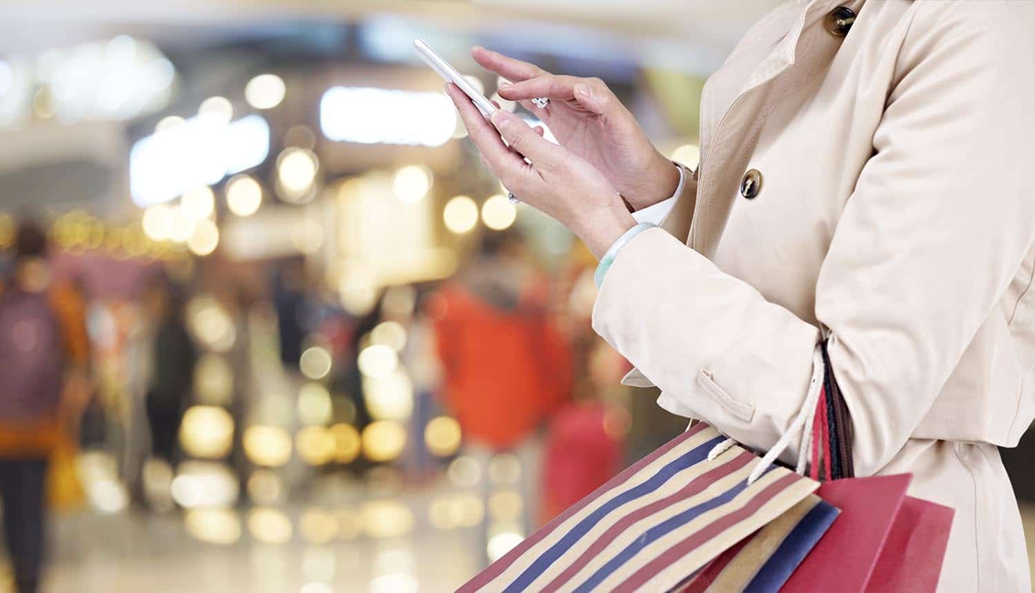Image of female shopper using mobile phone signifying how retailers can boost consumer trust by offering identity protection for holiday shoppers