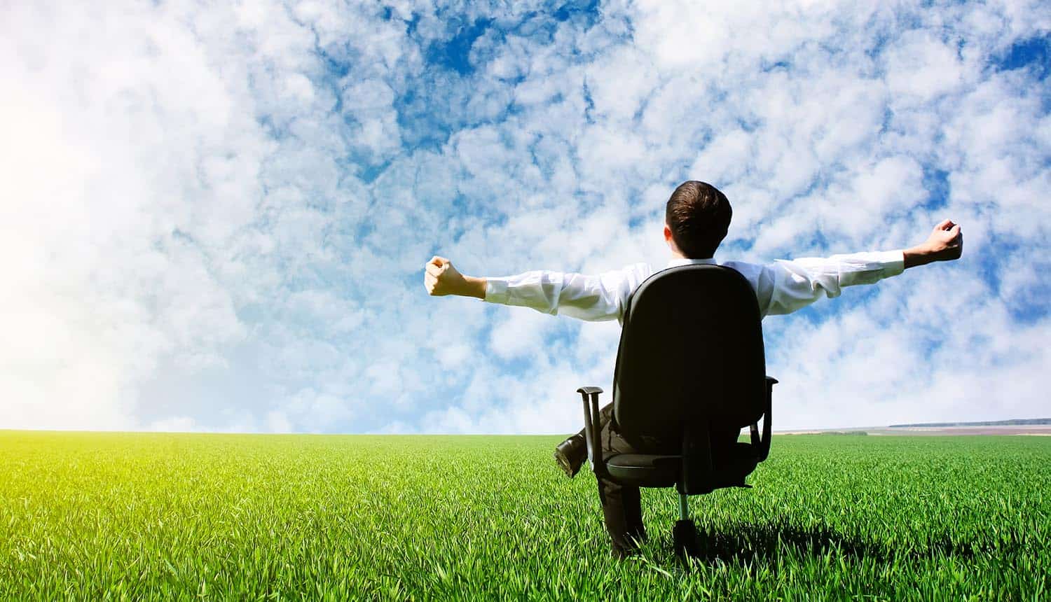 Image of businessman sitting in office chair with arms wide open looking at the sky representing businesses embracing cloud technology