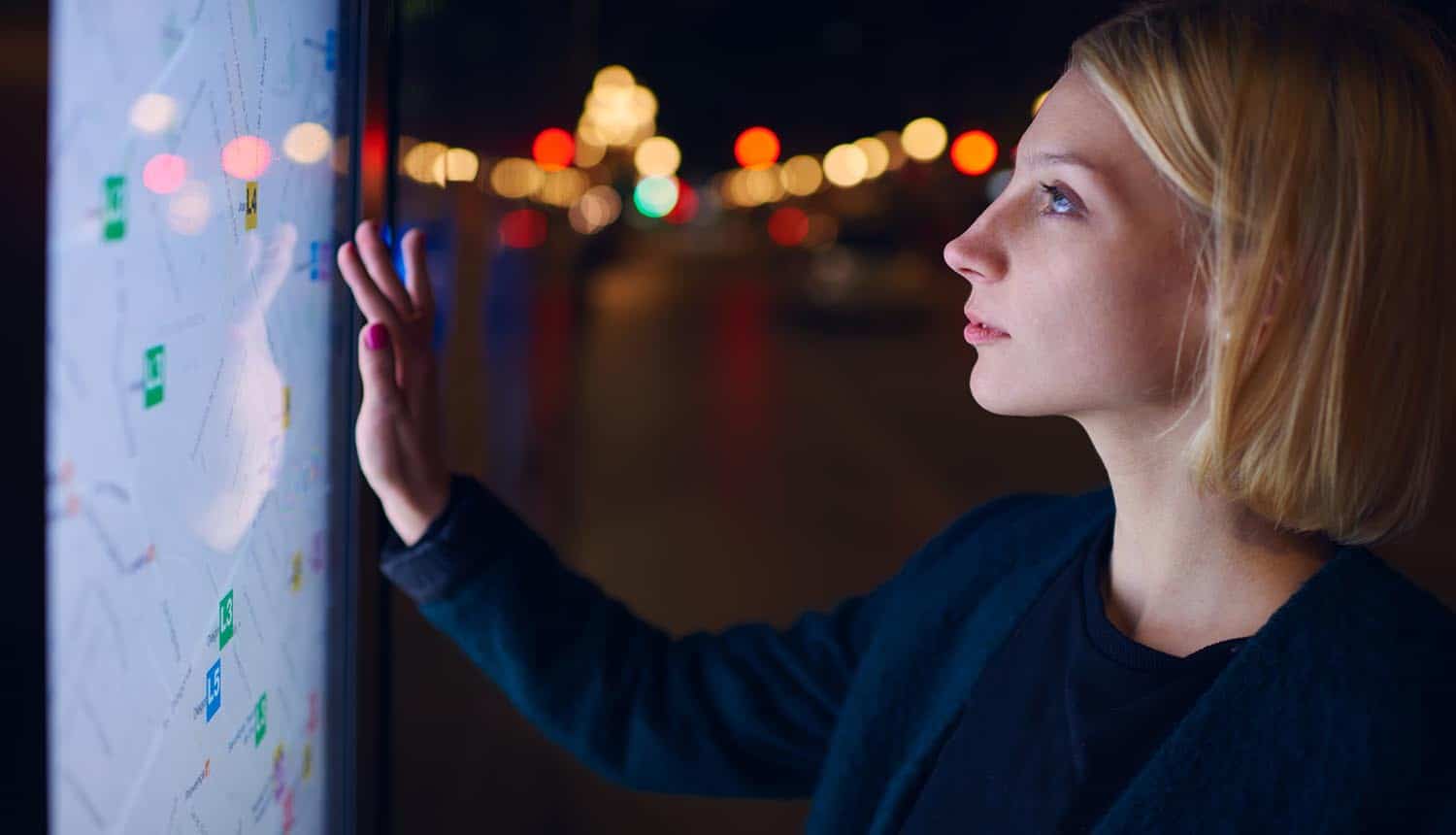 Image of woman standing in front of big screen and using it to find directions in smart city and the need for smart privacy