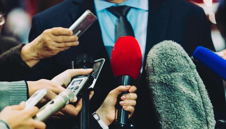 Image of man wearing a tie in front of microphones doing a media interview on data breaches for Under Armour and Panera Bread