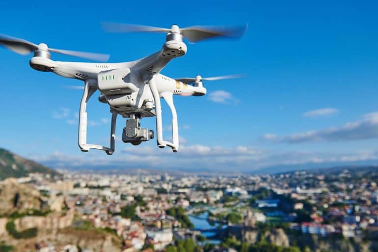 Image of drone flying as a eye in the sky against city backdrop signifying drone surveillance and the concern with privacy