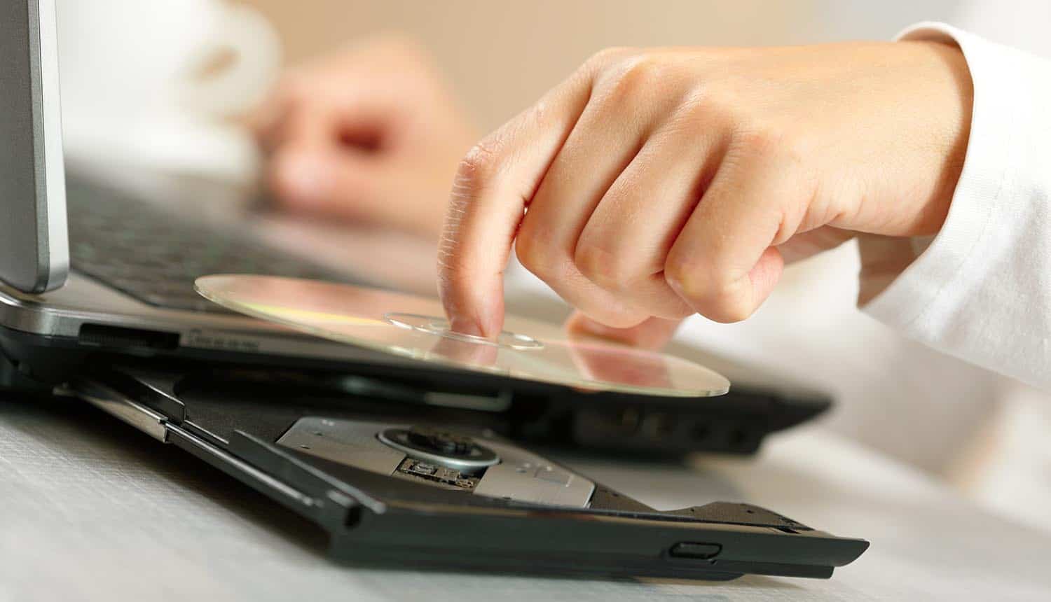 Image of hand putting CD in the tray of a laptop signifying the difficulty to know where your data is