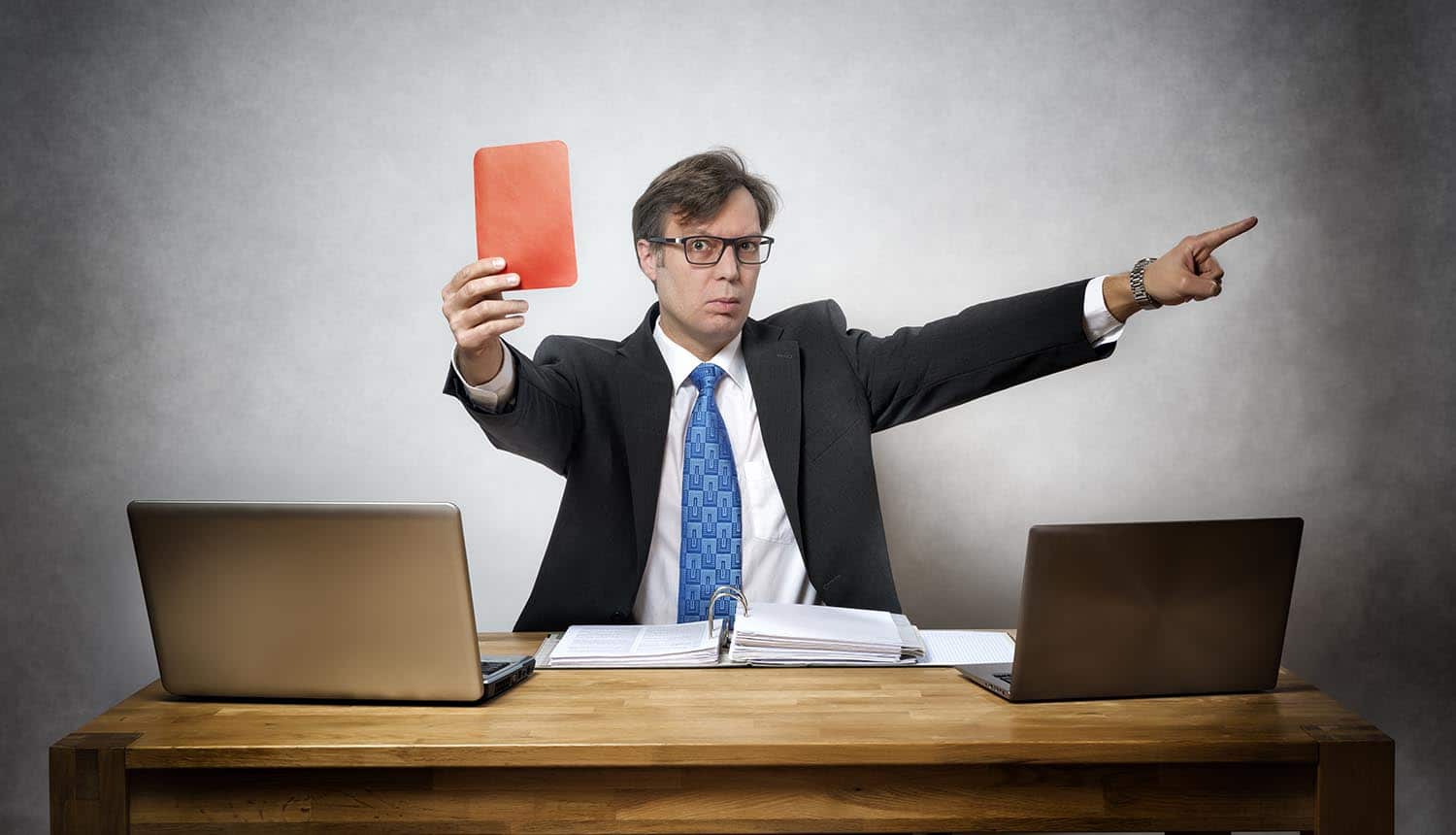 Image of man making judgement and holding up a red card showing the difficulty of regulating privacy as shown by the Facebook Cambridge Analytica case