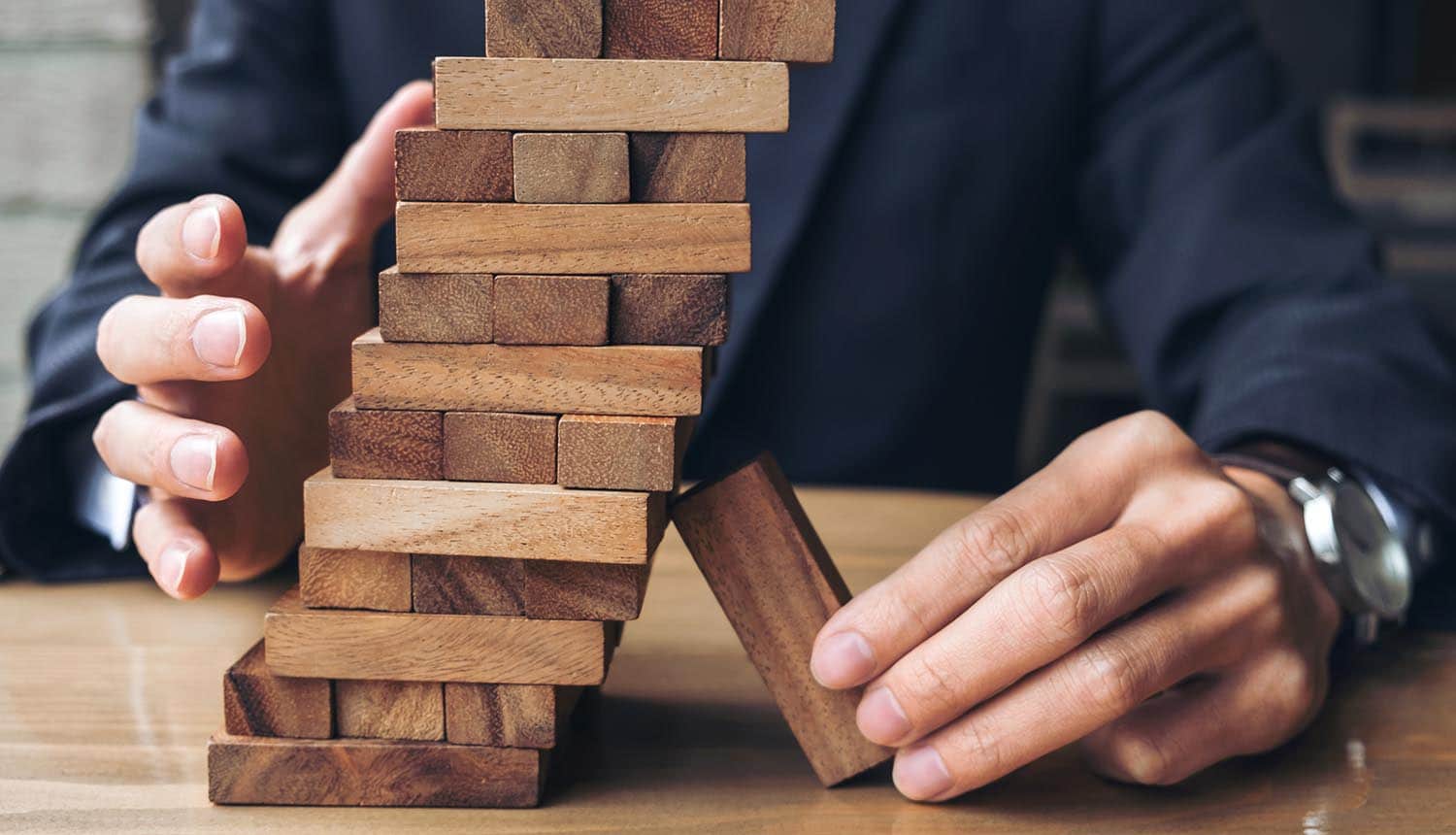 Image of man propping up a stack of blocks using a block showing how Big Tech are too big to fail and will require government support