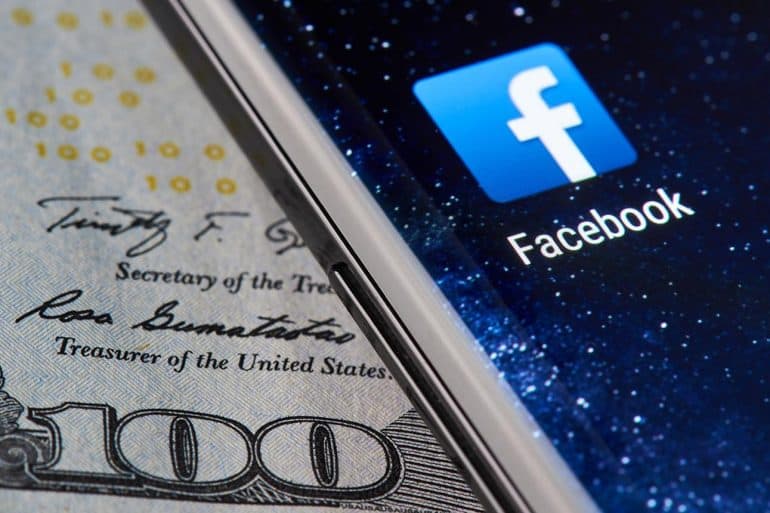 Facebook icon app on smartphone close-up on dollar currency