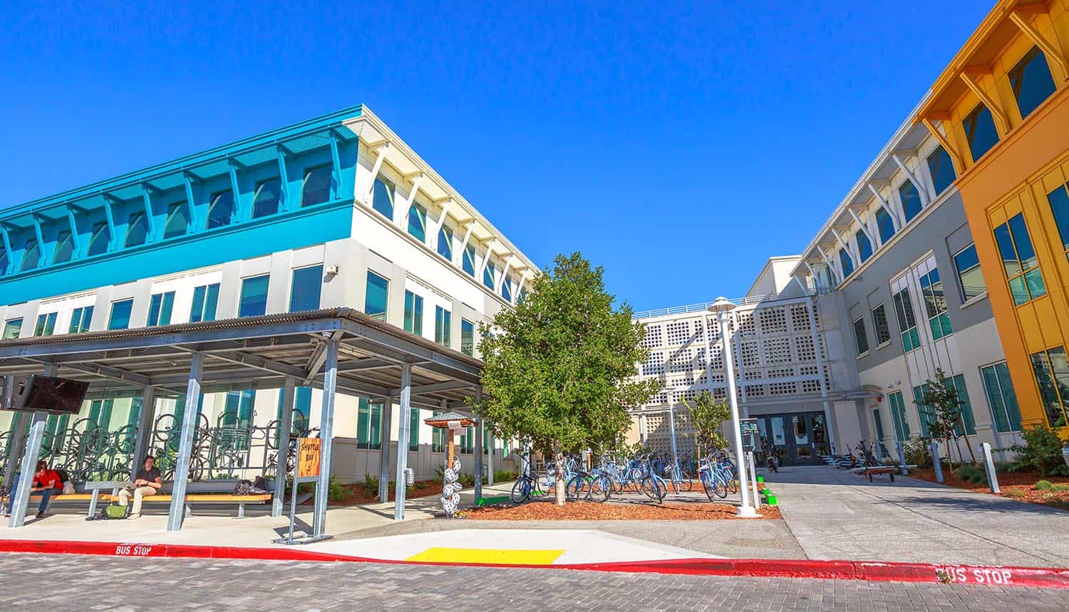 Main entrance of Facebook headquarters building with parking and corporate branded blue bicycles