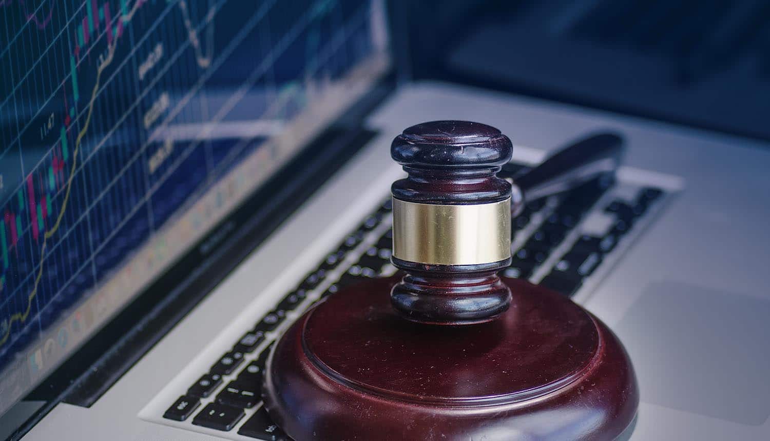 Image of hammer and gavel in front of computer screen as cyber crime legal law concept