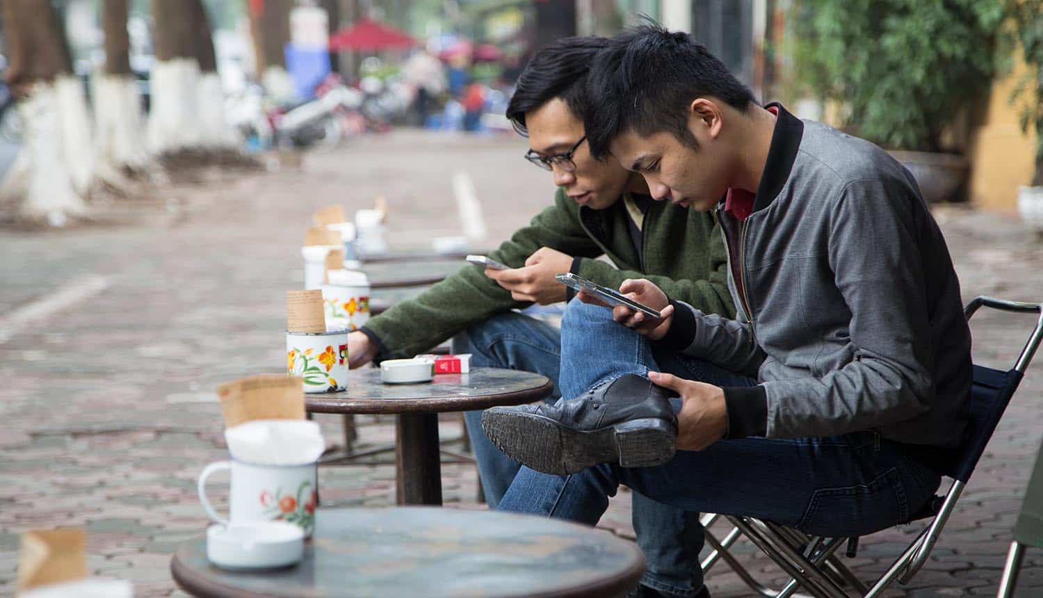 Vietnamese drinking coffee on the sidewalk and using mobile phones