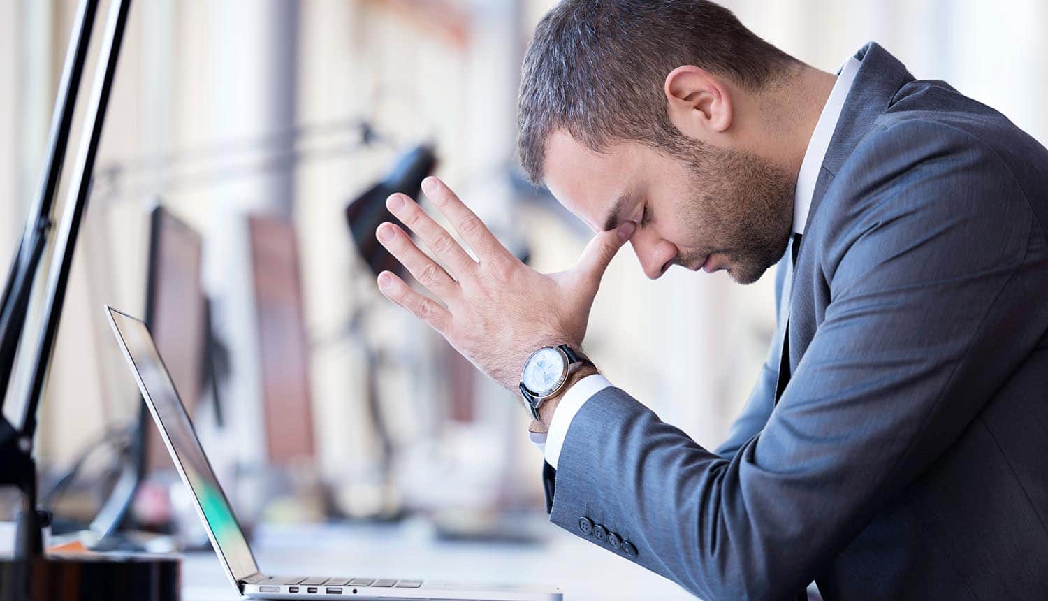 Frustrated small and medium business *SMB) owner working on laptop computer at office