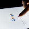 A woman's hand is touching screen on tablet computer for Google search engine.
