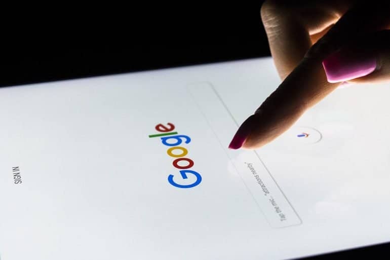 A woman's hand is touching screen on tablet computer for Google search engine.