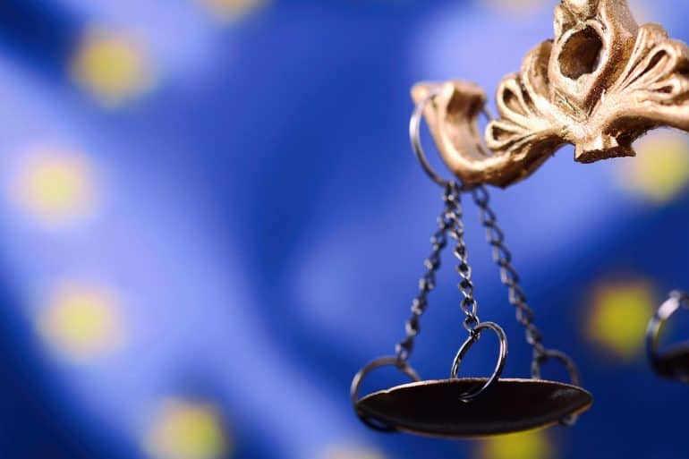 Scales of Justice in front of the European Union flag in the background.