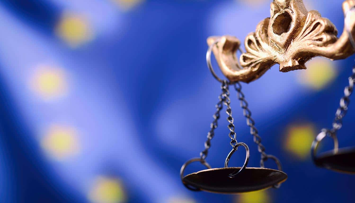 Scales of Justice in front of the European Union flag in the background.