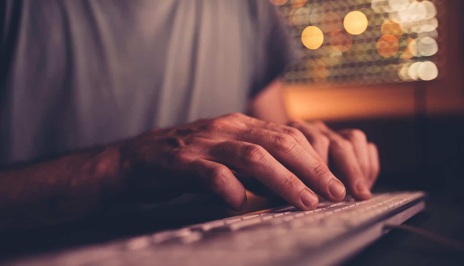 Man typing on keyboard of desktop PC showing the dangers of insider threats
