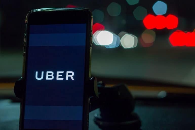 Smartphone attached to a car mount in car with Uber logo at night showing lessons from the Uber breach settlement