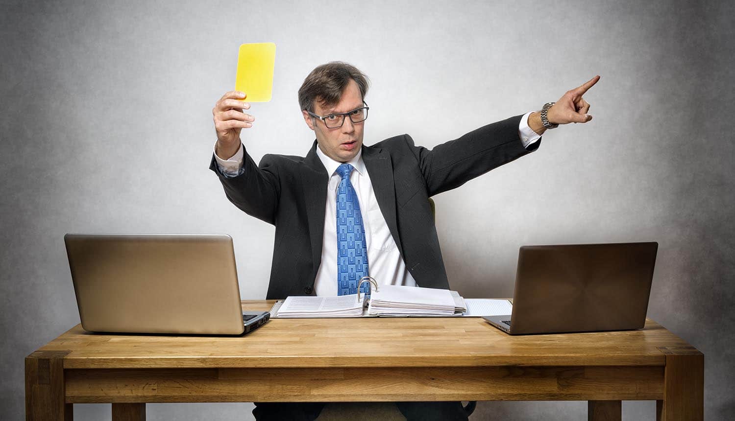 Regulator holding up yellow card in office showing the millions in ICO fines levied for 2018