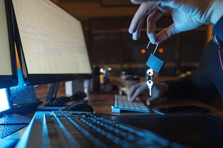 Close up hand of cybercriminal downloading data from Marriot data breach while holding an opened lock and key