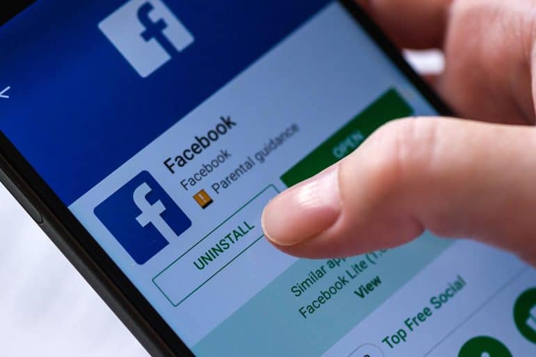 Finger hovering over uninstall button for Facebook app showing a woeful year for Facebook