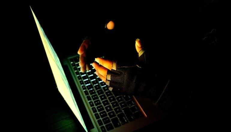 Human hand on the keyboard of notebook in the darkness. showing cyber fraud by Chinese hackers