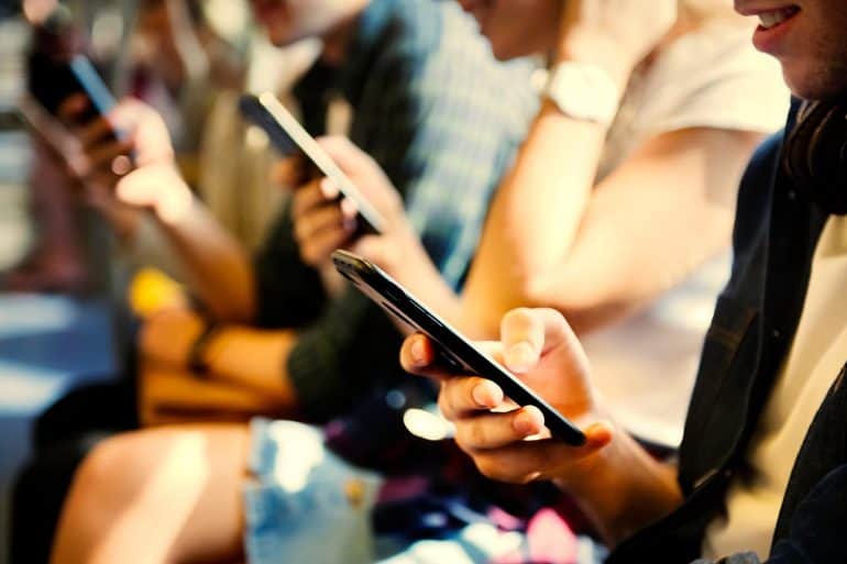 Young people using their smartphones showing that they will not pay for online privacy