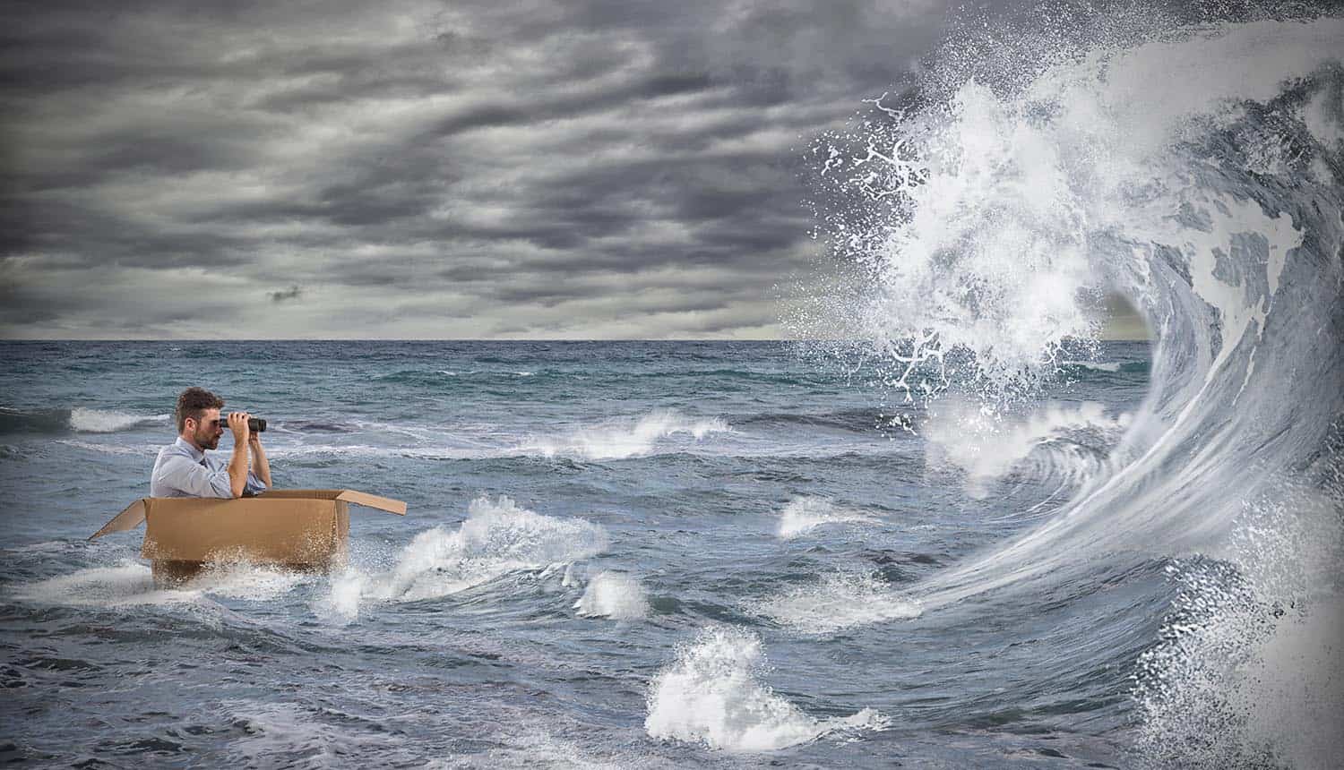 Businessman in a cardboard sails in a storm at sea, looking ahead using binoculars at the threat landscape