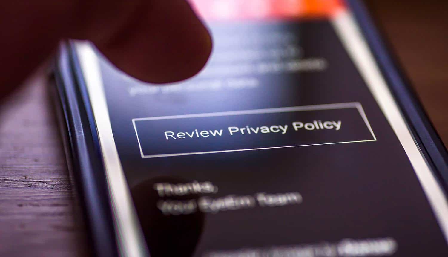 Closeup of human finger pointing to smartphone message with button Review Privacy Policy showing the problem with GDPR and transparency