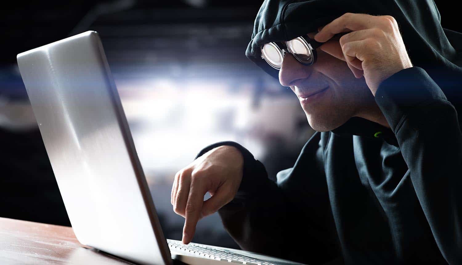 Hacker in front of his computer performing a formjacking attack