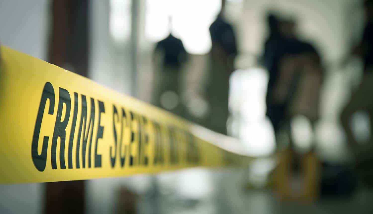 Crime scene tape with blurred forensic law enforcement background showing need for digital forensics