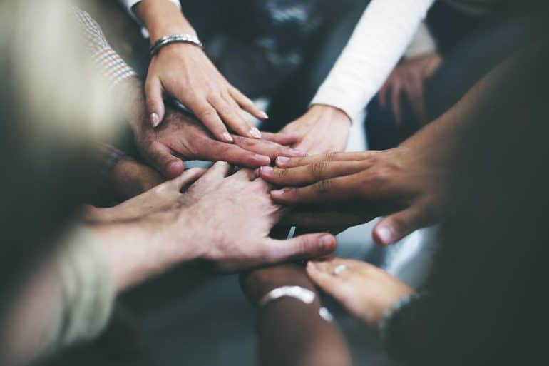Joining hands together as a team showing the need to focus on both information security and data privacy