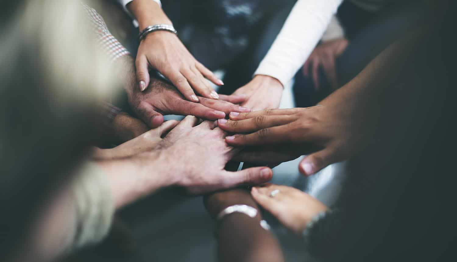 Joining hands together as a team showing the need to focus on both information security and data privacy