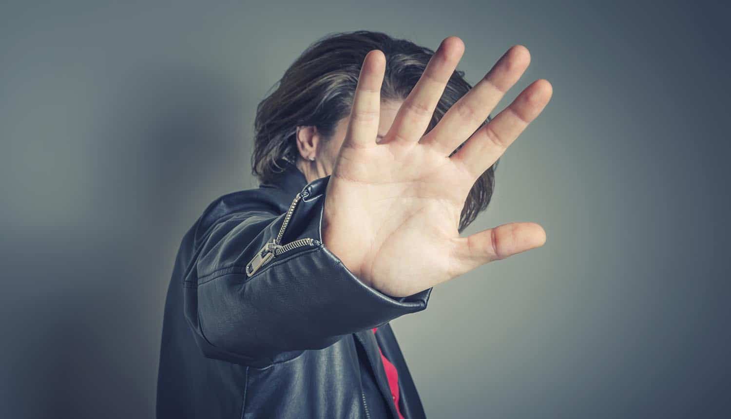 Celebrity is hiding face with a hand from newspaper photographers