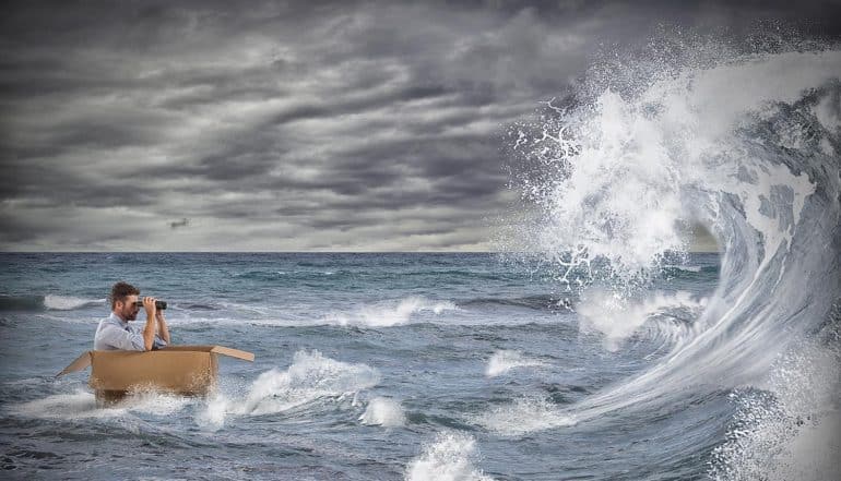 Businessman in a cardboard sails in a storm at sea showing how organizations cope with GDPR and CCPA regulations