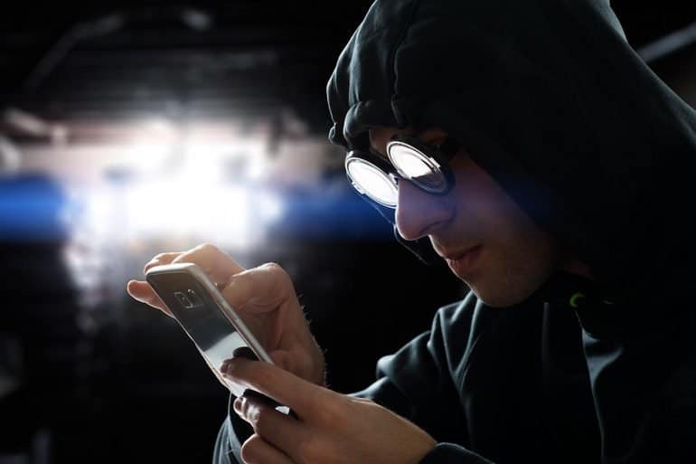 Hacker touching a smart phone screen showing how hackers attack mobile apps and the methods to protect against it