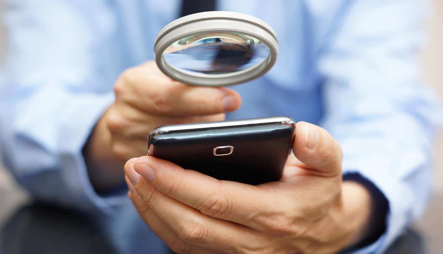 Businessman using mobile smart phone with magnifying glass showing many ways which mobile opens the door for fraud