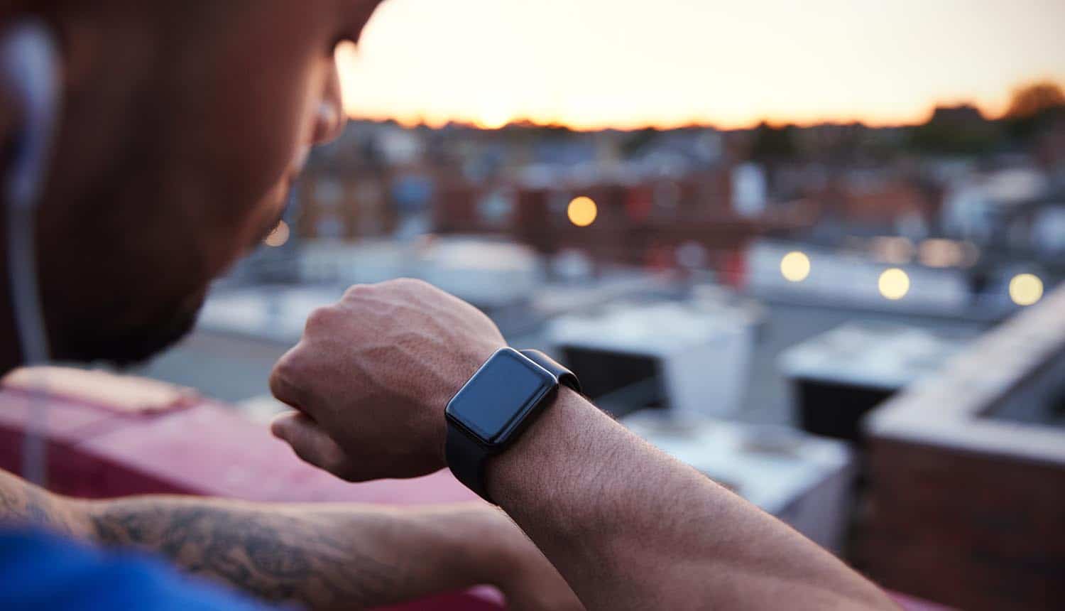 Runner checking fitness tracker showing potential use of fitness tracker technology to defend against cyber attacks