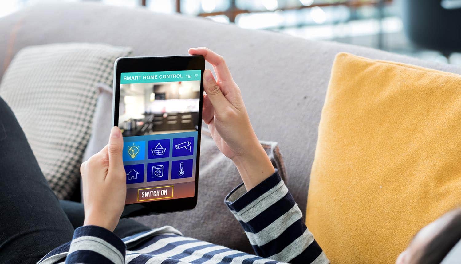 Hand on tablet using smart home system showing new IoT security laws in U.K. and U.S. to protect consumers from hacks of internet-connected devices