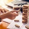 Hands building tower with wooden blocks showing how companies should carry out effective vendor risk management