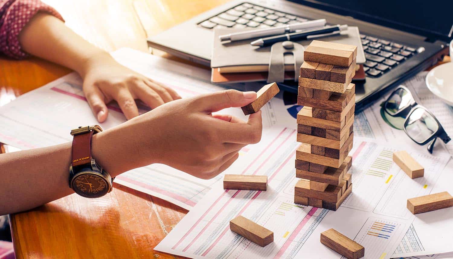 Hands building tower with wooden blocks showing how companies should carry out effective vendor risk management