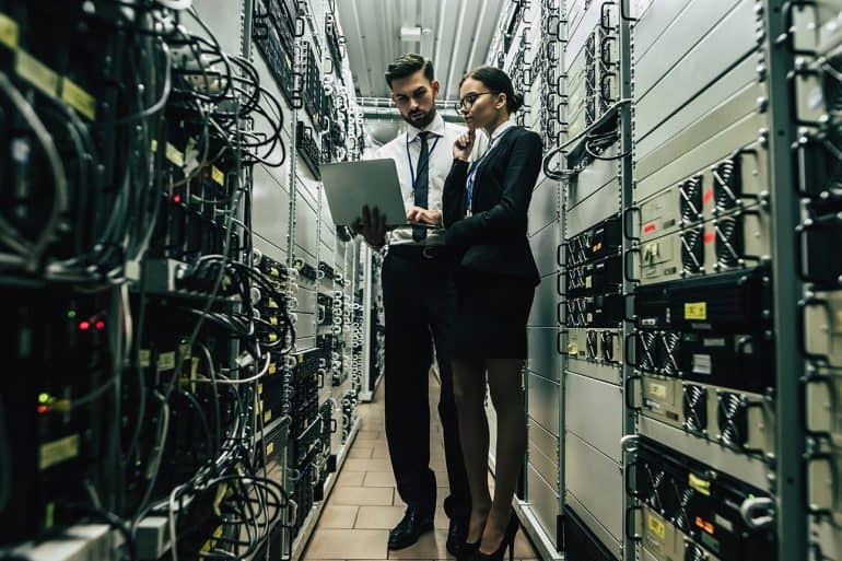 Technicians in data center examining servers showing the importance of finding legacy applications to prevent data breach